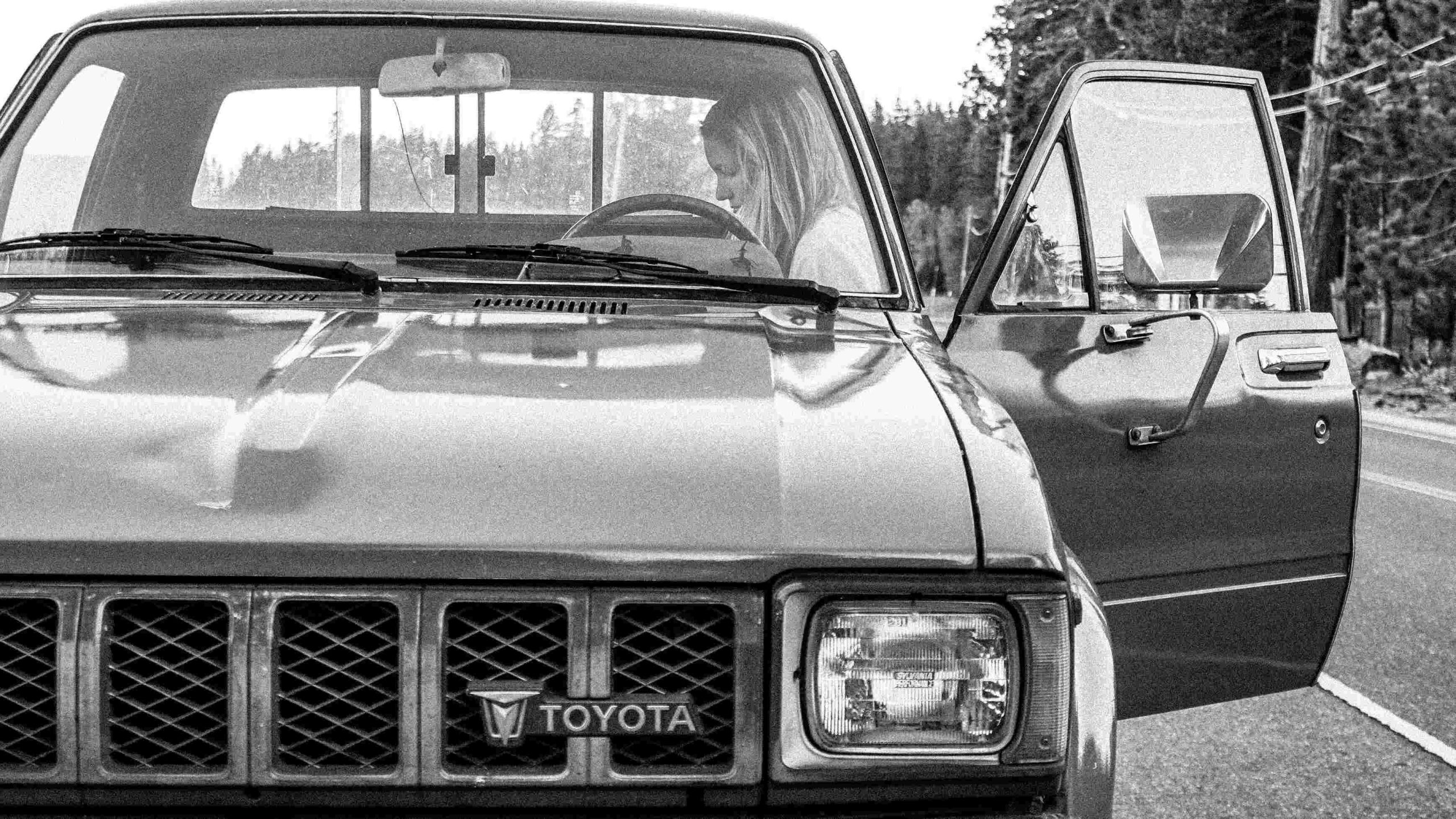 Grayscale Photo of a Woman in a Toyota Car 